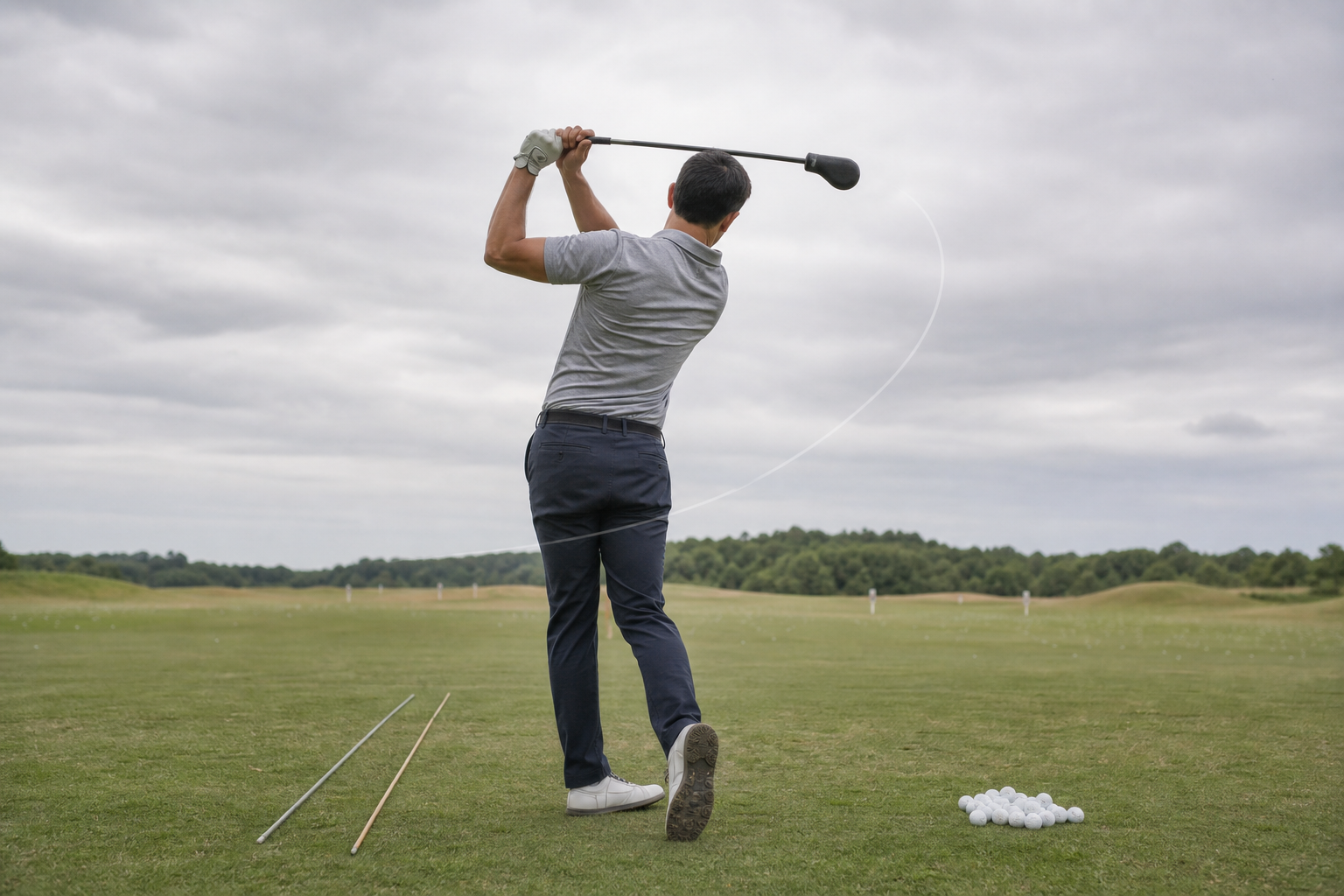 Golfer comparing straight alignment references on the ground with a smooth practice swing using a plain weighted training aid.